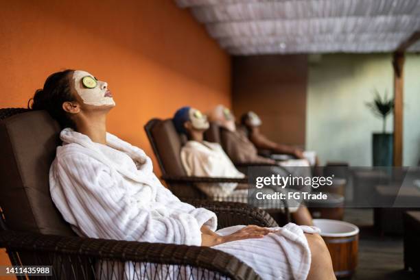 group of people in a spa doing a foot treatment with facial mask and cucumbers covering eyes - facial cleanse stock pictures, royalty-free photos & images