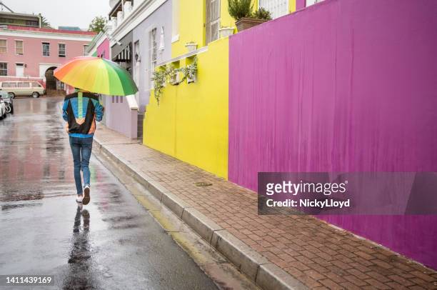 young man with a colorful umbrella walking down a street in the rain - cape town bo kaap stock pictures, royalty-free photos & images