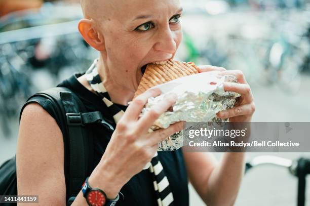 woman eating a döner kebab on a street - kebab stock-fotos und bilder