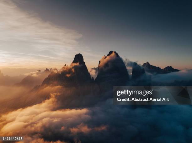 tre cime di lavaredo surrounded by clouds on a summers evening seen from a drone, dolomites, italy - veneto stockfoto's en -beelden