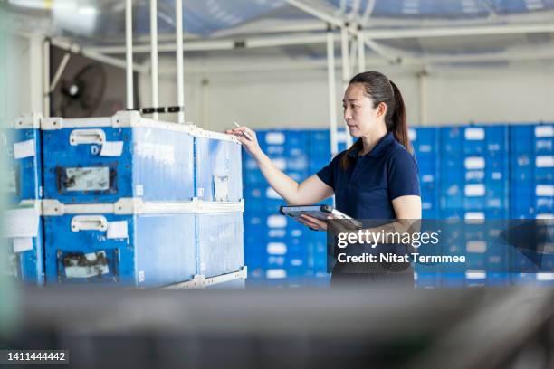 a warehouse front-line manager opportunity in logistics supply chain. an asian female warehouse supervisor uses a digital computer to manage or check overall warehouse operation in a factory distribution warehouse. - an vorderster front berufsbeschäftigung stock-fotos und bilder