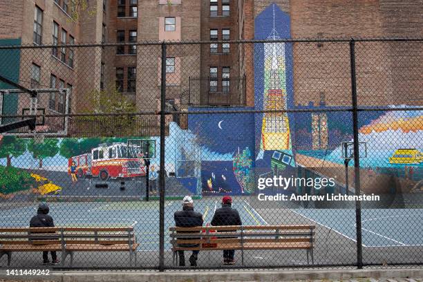 Residents sit on a bench in a park decorated with drawings of the old and new World Trade Centers on April 25, 2022 in the historical Lower East Side...