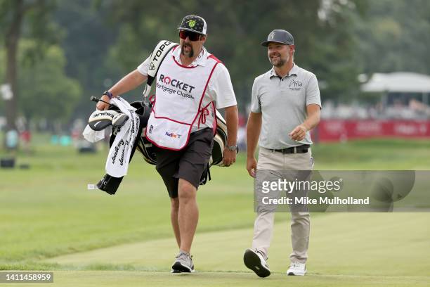 Ryan Moore of the United States and his caddie walk across the 16th hole during the first round of the Rocket Mortgage Classic at Detroit Golf Club...