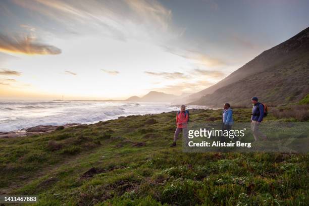 senior friends hiking together by the sea - stimmungsvoller himmel stock-fotos und bilder