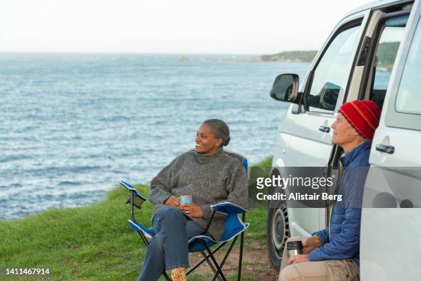 senior couple enjoying time by the sea with their camper van - early retirement stockfoto's en -beelden