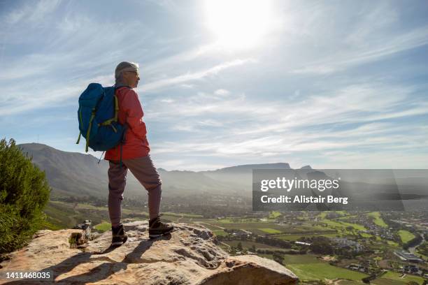 senior woman resting at the summit of a hike - jong van hart stockfoto's en -beelden