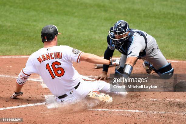 Trey Mancini of the Baltimore Orioles beats the tag by Rene Pinto for an inside the park home in the eight inning during a baseball game at Oriole...
