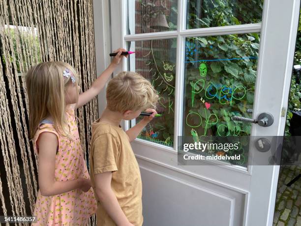 brother and sister children making a window paint - holland achtertuin stockfoto's en -beelden