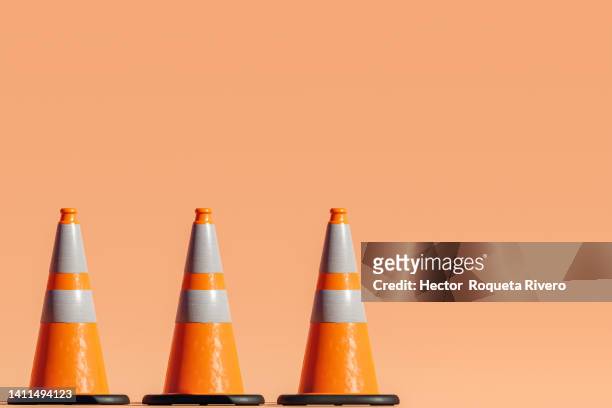 3d render of many traffic cones on orange background - verkehrshütchen stock-fotos und bilder