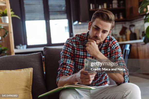 young man thinks about rising costs - counting imagens e fotografias de stock