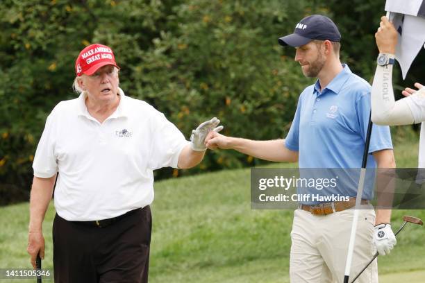 Former U.S. President Donald Trump and son Eric Trump react to his putt on the 14th green during the pro-am prior to the LIV Golf Invitational -...