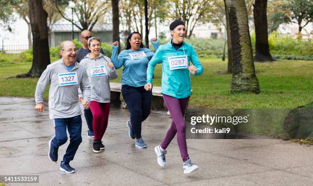 multiracial mature and senior adults running in race - mixed race woman stockfoto's en -beelden