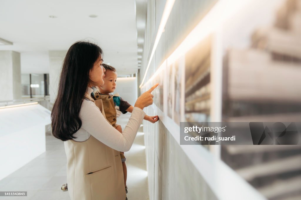 Asian women watching the exhibition with her baby in art gallery