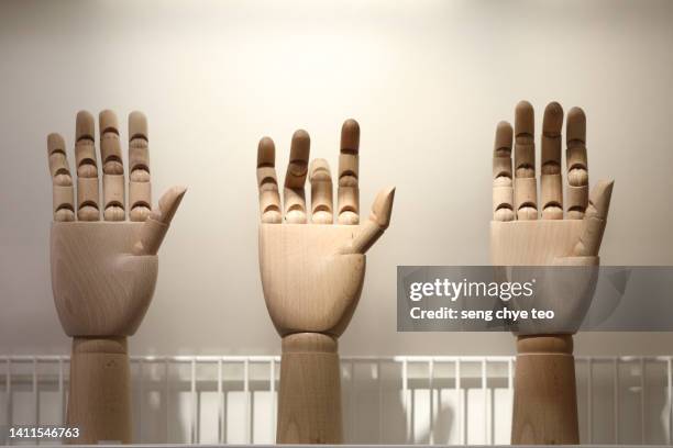 Closeup Of Wooden Figurine Hand Against Grey Background, Stockfoto
