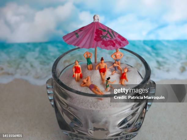 miniature people on the beach - cocktail umbrella stock pictures, royalty-free photos & images