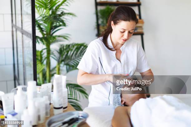 cosmetologist making face massage at home - schoonheidsspecialist stockfoto's en -beelden