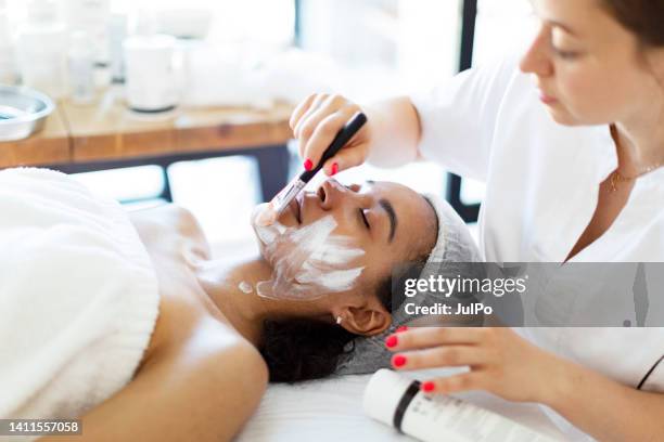cosmétologue faisant des massages du visage à la maison - spécialiste de la beauté photos et images de collection