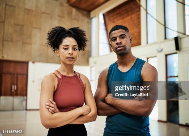 two african fitness instructors inside a workout center. portrait of afro american man and woman with arms folded looking confident, powerful and healthy in a sports studio or a wellness gym - center athlete stockfoto's en -beelden