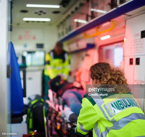 rettungspersonal lädt krankenwagen - rettungswagen stock-fotos und bilder