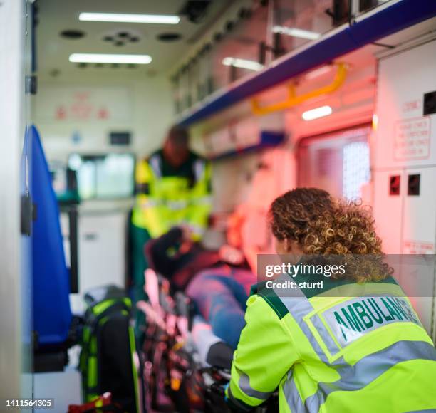 ambulance staff loading ambulance - ambulance stockfoto's en -beelden