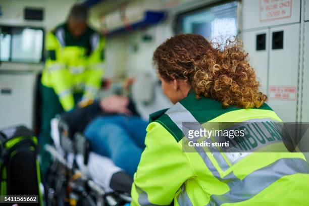 ambulance staff loading ambulance - emergency services uk stock pictures, royalty-free photos & images
