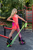 girl in a dress and special shoes for jumping is engaged in exercise equipment on the street.