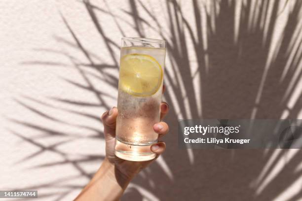 glass of water with lemon in women's hand. - lemon juice bildbanksfoton och bilder