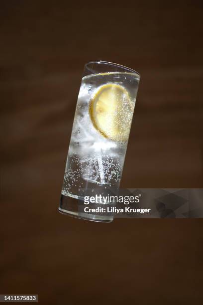 glass of water with lemons in the air on a dark background. - soft drink stock-fotos und bilder