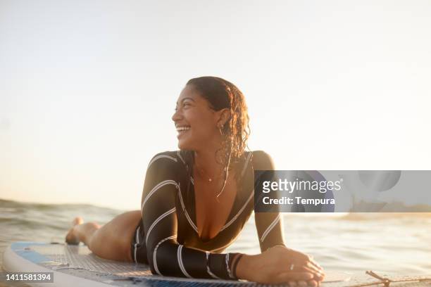 a woman enjoys a beautiful afternoon floating on a paddleboard. - golden hour woman stock pictures, royalty-free photos & images
