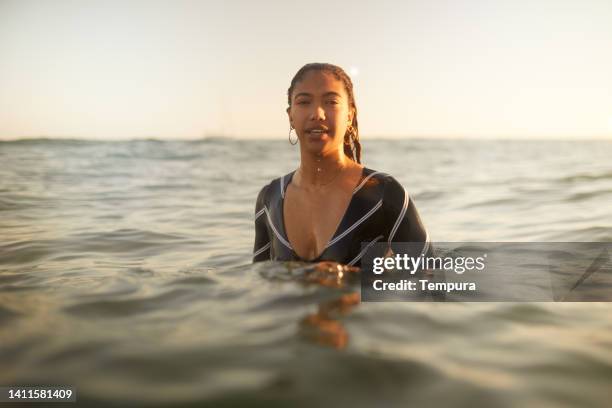 a young woman is enjoying a swim at the golden hour. - golden hour woman stock pictures, royalty-free photos & images