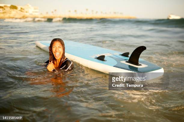 a woman laughs after a paddle surf wipeout - wipeout stock pictures, royalty-free photos & images