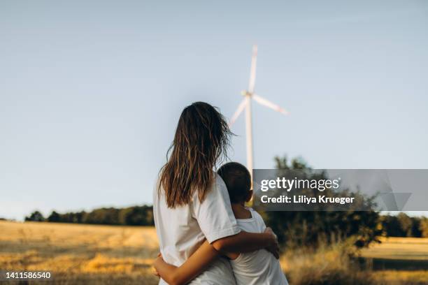 mother with son in front of windmill from the back. - fábricas tradicionales fotografías e imágenes de stock