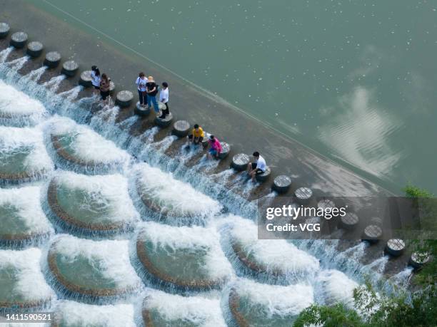 Tourists cool off at a location known for fish scale-shaped barriers that form small waterfalls during a hot summer day on July 28, 2022 in Xianfeng...