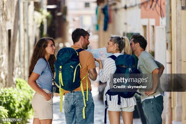 rear view of backpackers analyzing a map on the street. - istrië stockfoto's en -beelden