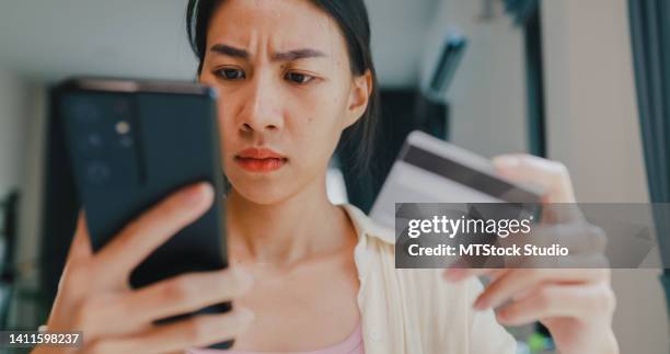 gros plan youth asia femme porter décontracté assis devant la réception tenir smartphone et carte de crédit se sentir contrarié achats en ligne paiement refusé crédit au-dessus de la limite dans le salon à la maison. - angry customer photos et images de collection