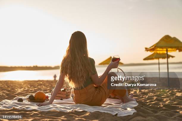 a beautiful woman at the back on the sandy shore. - picnic rug stockfoto's en -beelden