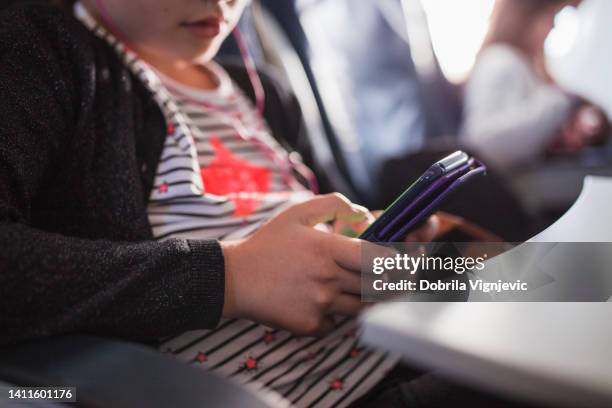 adolescente que usa un teléfono inteligente cuando viaja en avión, primer plano - procedimiento fotografías e imágenes de stock