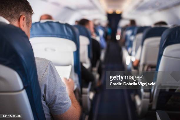 man reading on an airplane - ekonomiklass bildbanksfoton och bilder