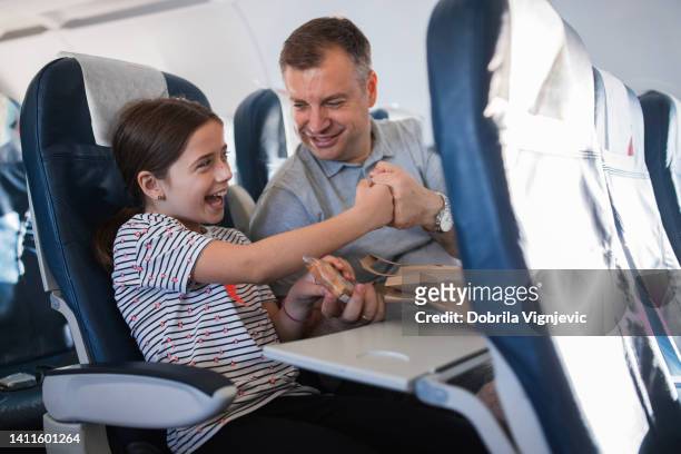 happy father and daughter having a fist bump when sharing sandwich - airplane seat stock pictures, royalty-free photos & images