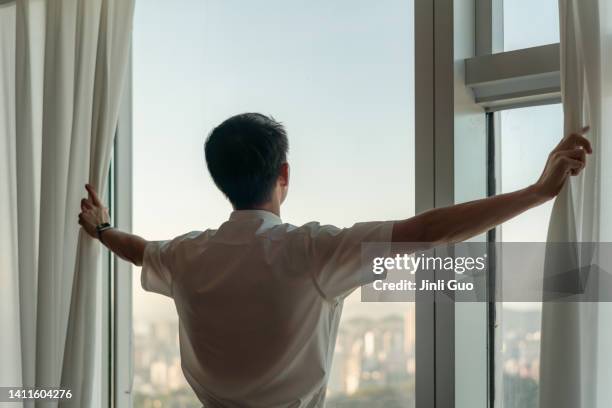 man opening curtains - man opening window stock pictures, royalty-free photos & images