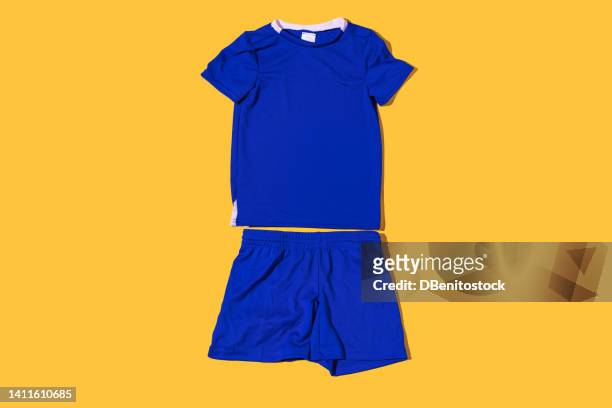 blue technical fabric soccer jersey and pants on a yellow background. concept of sport, soccer ball, uniform, world cup and kit. - soccer uniform foto e immagini stock