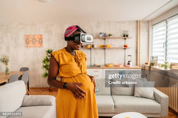 joven embarazada con un casco virtual de bienes raíces en una casa - 3d mom son fotografías e imágenes de stock