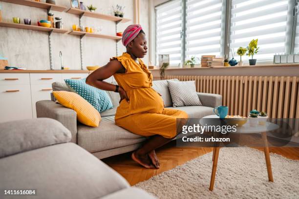 young pregnant woman suffering from backache - mid adult women stock pictures, royalty-free photos & images