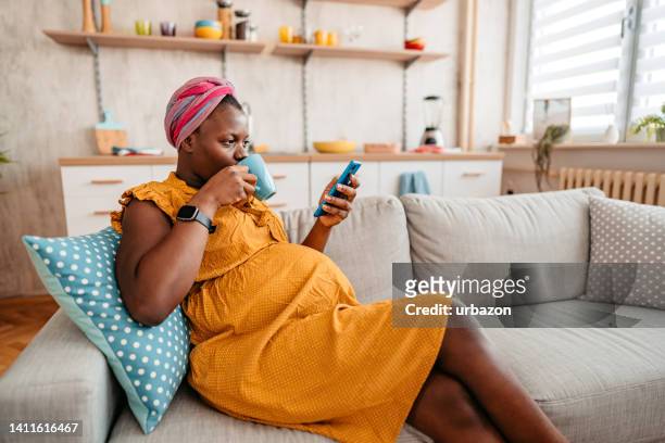 pregnant woman using smart phone and drinking coffee at home - pregnant coffee 個照片及圖片檔