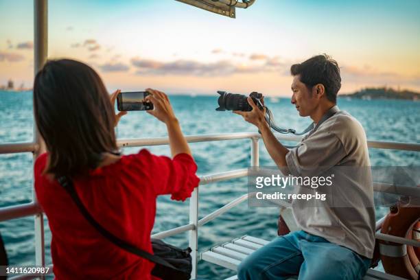 young couple tourists taking ferry tour during their travel - couple smartphone stockfoto's en -beelden