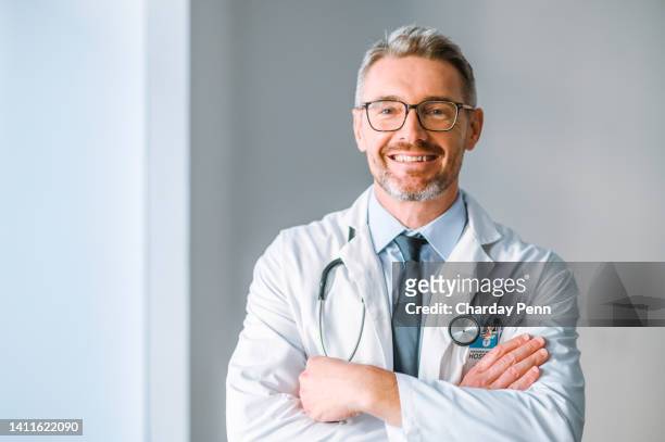 a confident and proud male medical doctor looking at the camera with copy space. portrait of a healthcare professional with a bright smile. an organized gp with a satisfying career at the hospital - gray coat stock pictures, royalty-free photos & images