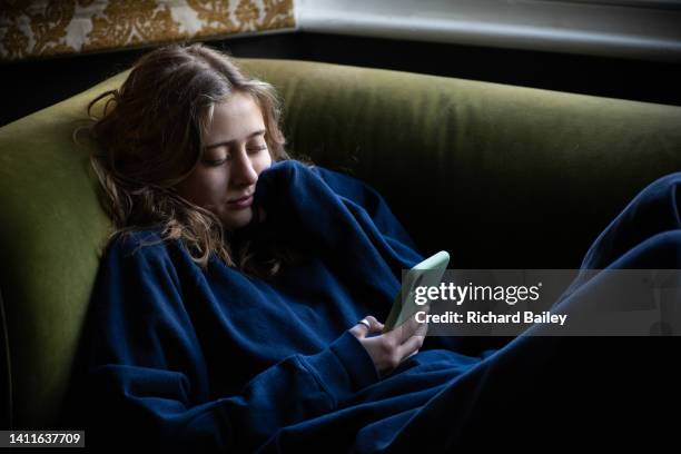 teenage girl reclining on sofa looking at her mobile phone - lying on back girl on the sofa stock pictures, royalty-free photos & images