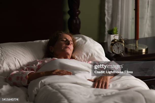 an anxious woman lying in bed ready to spring out. - alarm clock hand stock pictures, royalty-free photos & images