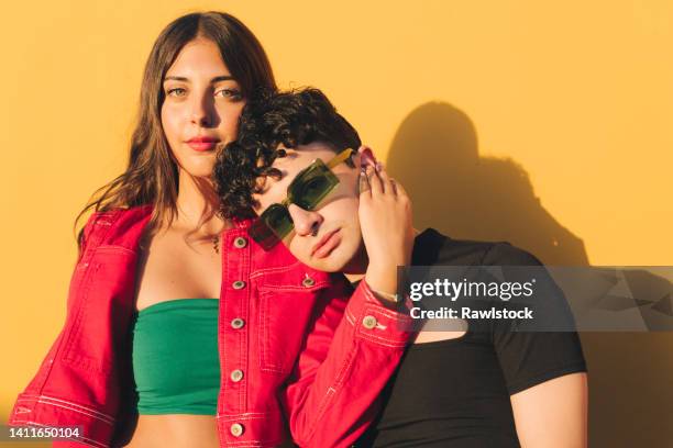 portrait of two young stylish boys on an orange background - fashion model couple stock pictures, royalty-free photos & images