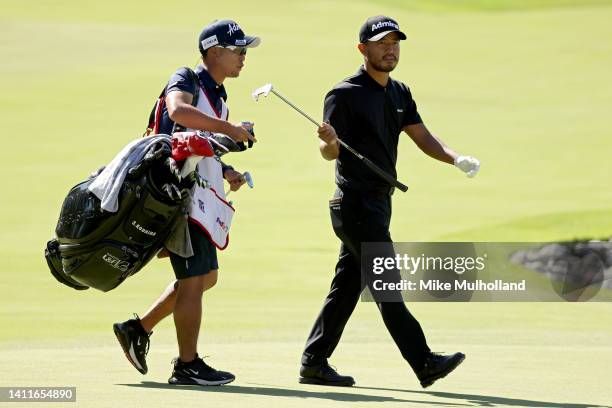 Satoshi Kodaira of Japan exchanges clubs with his caddie on the 14th green during the second round of the Rocket Mortgage Classic at Detroit Golf...